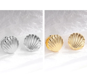Close-up of shell-textured earrings in gold and silver finishes on artistic paper