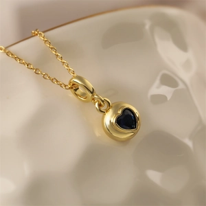 Macro shot of gold-plated circular pendant with a sparkling blue heart zirconia gemstone