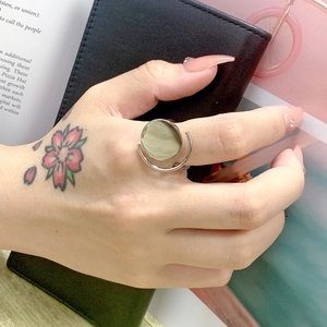 Silver titanium steel ring featuring a pale green gemstone on a lifestyle hand model