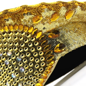 Close-up of golden bridal captain hat with sequins, amber rhinestones and lace