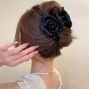 Dettaglio macro della molletta a rosa in tessuto nero indossata su uno chignon elegante