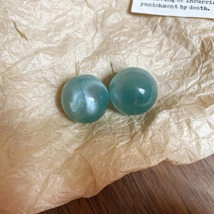 Macro shot of candy-colored turquoise round stud earrings on vintage kraft paper