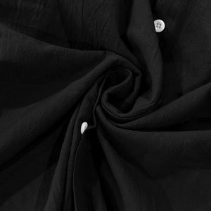 Détail du tissu en lin noir avec boutons blancs montrant la texture naturelle et douce