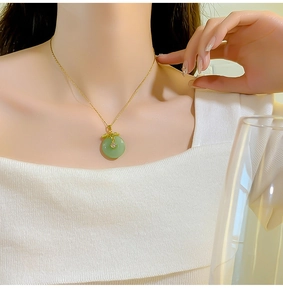 Close-up of light green jade平安扣 pendant necklace with gold leaf design on woman's neck