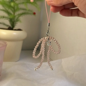 Close-up of pink beaded bow phone charm with star pendant and small pearls