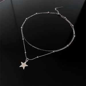 Close-up of double-layered silver star necklace featuring polished finish and bead chain