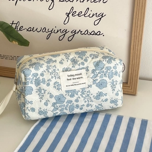 Close-up of blue floral quilted makeup bag with zipper and woven carry handle