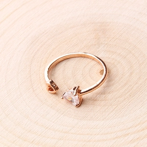 Detail of rose gold open ring with heart cutout and triangular zircon on wood