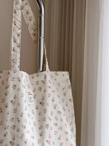 Detail of floral canvas tote bag featuring a decorative woven label and pink flower patterns