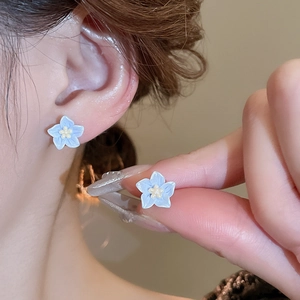 Vue rapprochée de boucles d'oreilles fleurs bleues avec pétales en émail dégradé