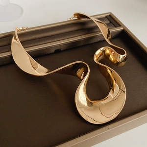 Detailed view of an abstract sculptural gold metal choker necklace on a jewelry tray