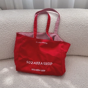 Detailansicht der roten Canvas-Tasche mit weißer Stickerei und gestreiftem Innenfutter