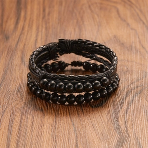 Macro shot of multi-layer black braided leather bracelet with glossy beads on wood