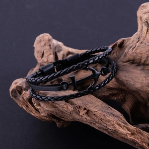 Close-up of a vintage anchor charm on a multi-layer black braided leather bracelet
