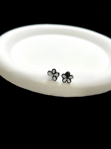 Detailed view of 3D white enamel flower earrings with black outlines and golden accents