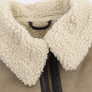 Detailed close-up of brown faux leather jacket collar with soft white shearling and metal zip