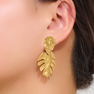 Elegant 18k gold plated monstera leaf drop earrings worn by a model in a profile view