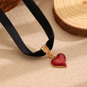 Dettaglio del ciondolo a cuore glitter rosso su choker in velluto nero con freccia