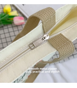 Detail of silver metallic zipper slider on sturdy off-white canvas shoulder bag