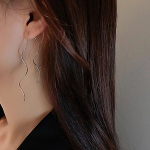 Close-up of elegant silver wavy threader earrings on model showing minimalist s-shape style