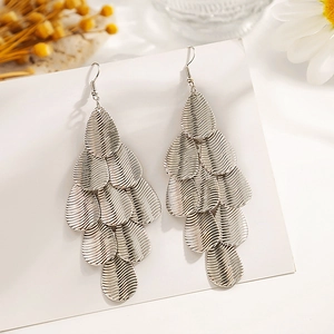 Détail de boucles d'oreilles feuilles argentées multicouches avec texture écailles