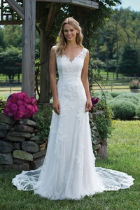 Détail de robe de mariée en dentelle blanche avec col en V, motifs floraux et longue traîne