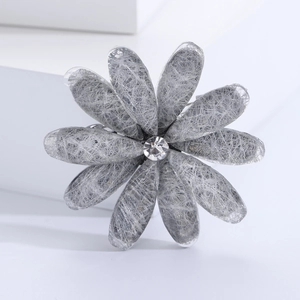 Macro shot of silver-gray flower brooch with metallic mesh petals and crystal center