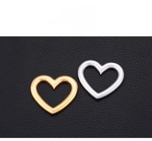 Detail of heart-shaped hollow pendants in gold and silver finishes on black leather