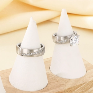 Detailed view of silver couple rings with brilliant zircon stones on white cone stands