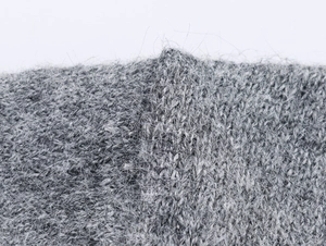 Gros plan sur le tricot gris duveteux montrant la texture douce de la laine mohair