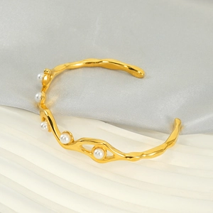 Detail view of wave-shaped gold-plated stainless steel bracelet with five white pearls