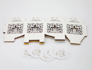 Detail van wit lasergesneden bedankdoosje met kruismotief en elegant cadeaulabel