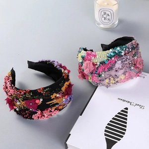 Wide headband with colorful sequins, lace flowers, and pearls on a light grey background