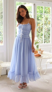 Détail d'une robe d'été bleu clair avec cordons blancs et volants superposés