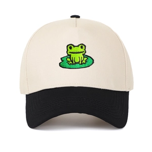 Close-up of embroidered green frog on lotus leaf on ivory and black trucker hat