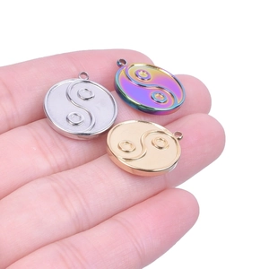 Three Tai Chi Yin Yang pendants in silver, gold, and rainbow colors on fingertips