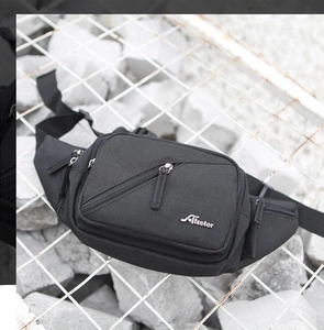 Close-up of black nylon waist bag with metal logo on industrial stone background