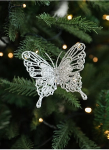 Gros plan d'un papillon pailleté argenté ajouré décorant un sapin de Noël illuminé