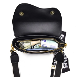 Chic black saddle bag with wide shoulder strap and silk scarf showing spacious interior