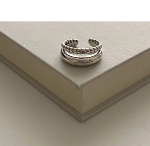 Macro shot of minimalist S925 sterling silver double-layer twisted ring on a book