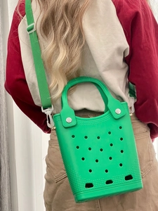 Green EVA beach bag with holes and matching shoulder strap worn by a person