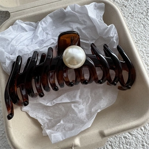 Close-up of large amber hair claw clip with pearl accent in an eco-friendly gift box