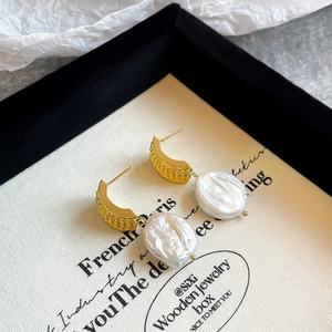 Detailed macro shot of baroque pearls on gold C-shaped earrings with tassel design