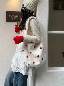 Close-up of white plush tote bag featuring red heart embroidery for winter fashion
