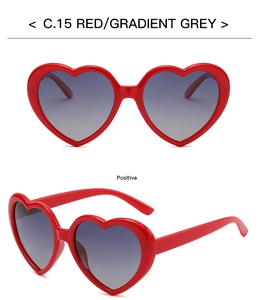 Detail view of heart-shaped sunglasses with red frames and gradient grey lenses