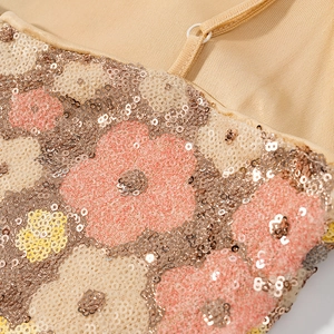 Close-up of floral sequin embroidery and delicate spaghetti straps on a beige party dress