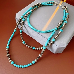 Dettaglio della collana multistrato boho con perle turchesi e argentate su un espositore