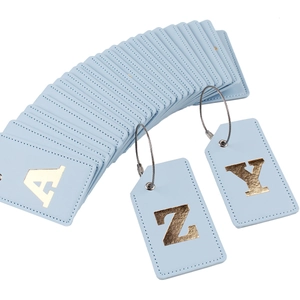 Detail of light blue PU leather luggage tags with gold foil letters and steel loops