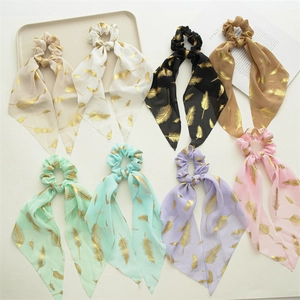 Detail view of colorful chiffon scrunchies with long ribbons and gold feather prints
