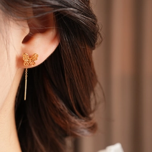 Close-up of a gold-plated butterfly tassel drop earring on a female model